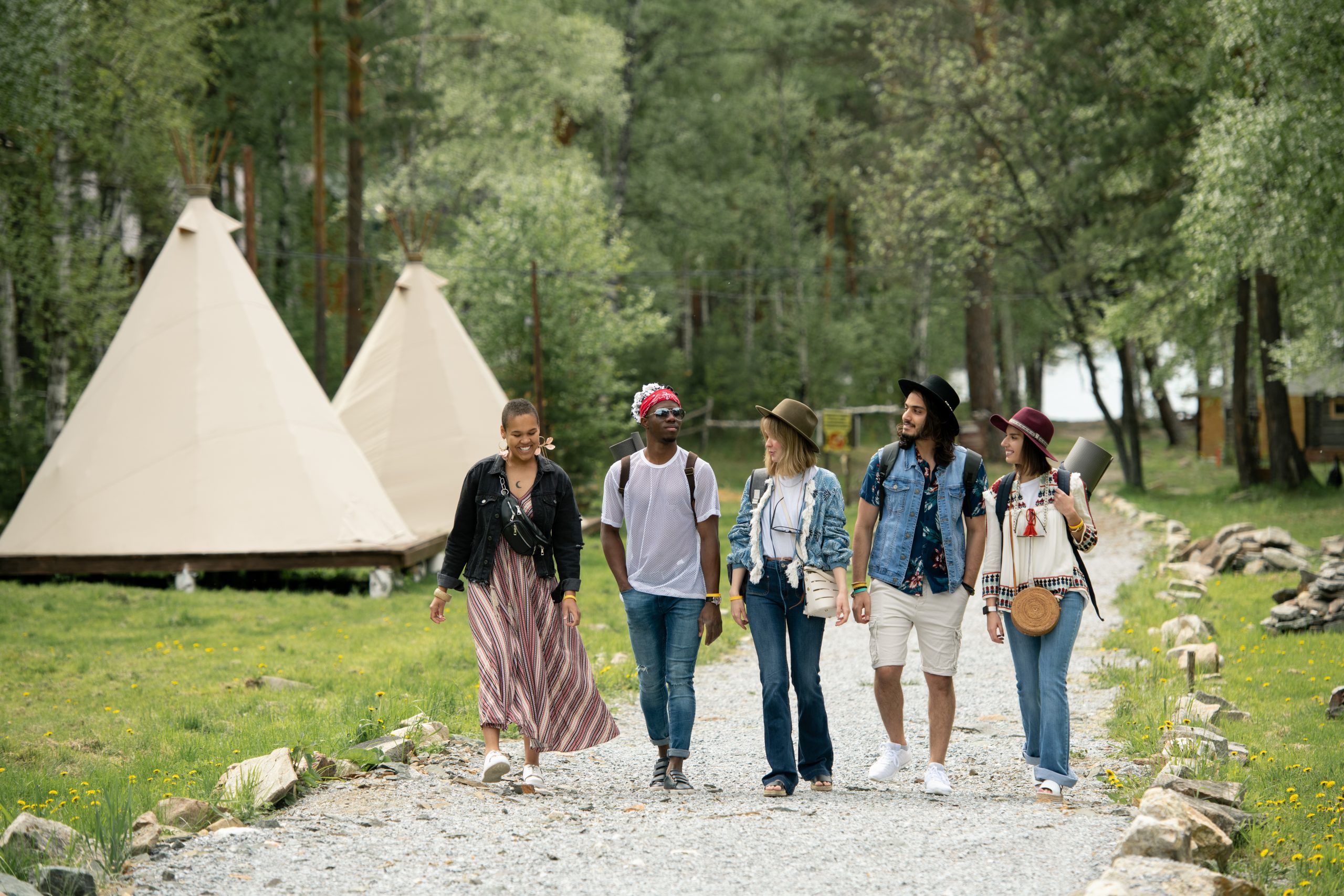 Group of young multi-ethnic people arrived at campsite walking over beautiful park